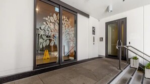 A modern building entrance with glass doors, a staircase, and a clean, tiled floor. - Central & Modern 2-Bedroom Apartment (Auckland)