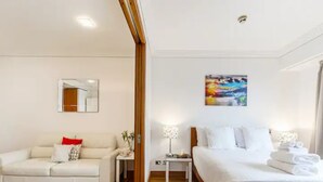 Une chambre d’hôtel avec un lit, un canapé, une table de chevet, une lampe, un tableau et un miroir.