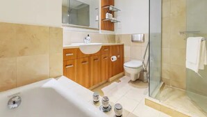 Une salle de bain moderne équipée d’une baignoire, de toilettes et d’une douche séparée par des parois en verre.