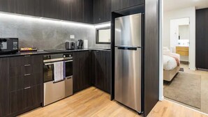 Una cocina moderna con armarios oscuros, electrodomésticos de acero inoxidable y suelo de madera.