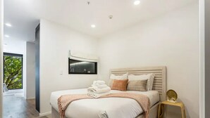 Un dormitorio moderno con una cama grande, una mesita de noche pequeña y vistas a zonas verdes.