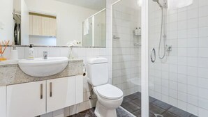 Ein modernes Badezimmer mit Waschbecken, Toilette und Dusche in Weiß.