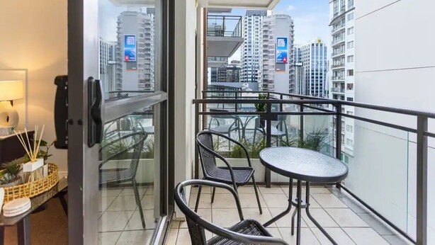 Ein Balkon mit Glastür, einem kleinen Tisch und zwei Stühlen.