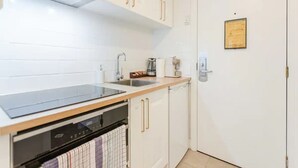 Eine moderne Küche mit weißen Schränken, einer schwarzen Arbeitsplatte, einem eingebauten Backofen und einer Kaffeemaschine.