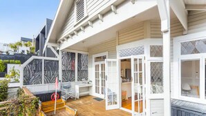 A covered outdoor area with a wooden deck, a seating area with a table and chairs, and a small boat-like structure. - Parnell Home With Stunning Views (Auckland)