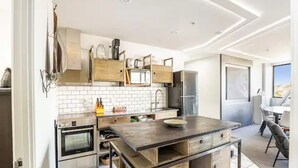 Een moderne keuken met een centraal eiland, inbouwapparatuur en uitzicht op het buiten.