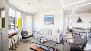 Een moderne woonkamer met een bank, fauteuils, een salontafel en een schilderij aan de muur.