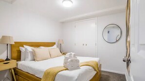 A hotel room with a bed, two bedside tables, a mirror, and a door.