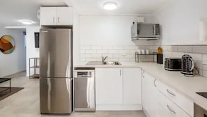A modern kitchen with stainless steel appliances, white cabinetry, and a tiled backsplash.