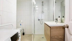 A modern bathroom with a shower, a toilet, and a vanity with a mirror.