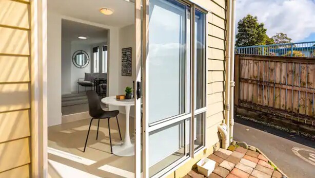 A modern house with a glass door leading to a dining area with a table and chairs. - Stunning Studio In Grey Lynn! (Auckland)