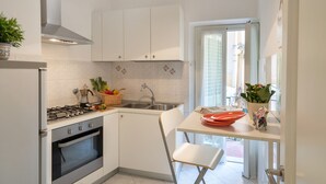 Een moderne keuken met witte kasten, een gasfornuis en een spoelbak. Er is een raam met uitzicht op de omgeving.