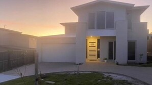 Una casa moderna de dos pisos con un césped cuidado y un camino de entrada con portón.