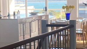 Una cocina moderna con un amplio ventanal que ofrece una vista panorámica del mar y las colinas.