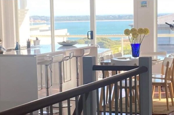 Een moderne keuken met een groot raam met uitzicht op zee en heuvels.