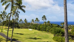 A golf course with palm trees and a view of the ocean. - 🌴 Newly Renovated Top Floor Condo with Golf Course & Ocean Views 🌴 (Kailua Kona)