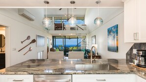 A modern kitchen with a large island, stainless steel appliances, and pendant lighting. - 🌴 Newly Renovated Top Floor Condo with Golf Course & Ocean Views 🌴 (Kailua Kona)