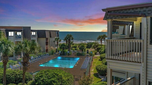 A pool area with a view of the ocean, surrounded by buildings with balconies. - Ocean Forest Villas Unit C301 - Ocean view (Myrtle Beach)