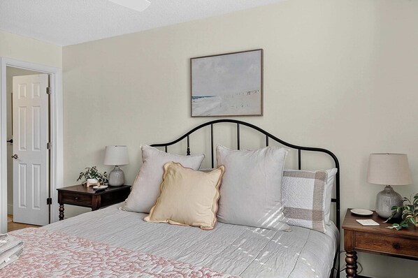 A neatly arranged bedroom with a bed, bedside tables, and a wall-mounted painting.