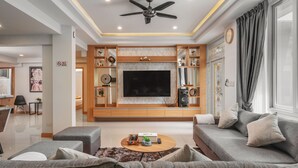 A modern living room with a flat-screen TV, grey sofas, a coffee table, and a ceiling fan. - Gala Pavilion (Pattaya)