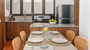 Eine moderne Küche mit Holzausstattung, einem Edelstahlkühlschrank und einem Essbereich mit Korbstühlen und einem Tisch für vier Personen.