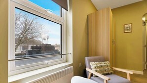 A room with a window, radiator, chair, and wooden panel wall. - Luxurious 1 Bedroom with Private Parking and Wifi (Middlesbrough)