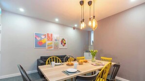 A dining area with a wooden table, yellow and black chairs, and a modern chandelier. - Luxurious 1 Bedroom with Private Parking and Wifi (Middlesbrough)