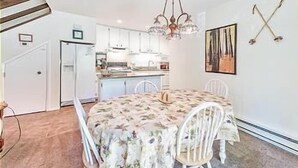 A dining area with a round table, white chairs, and a chandelier. - 45 Coeur Du Lac 3BR/2BA Incline Village, Pool & Mtn View (Incline Village)