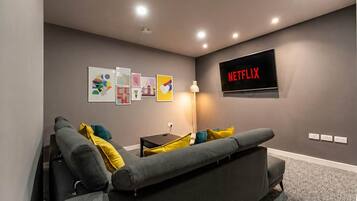 A modern living room with a gray sofa, a flat-screen TV, and wall art.
