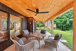 An outdoor patio with wicker furniture, a table, and a ceiling fan.