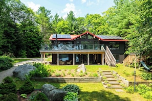 A modern house with a large deck, solar panels, and a garden.