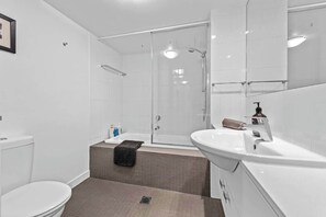 Une salle de bain moderne équipée de toilettes, d’un lavabo, d’une douche et d’une baignoire.