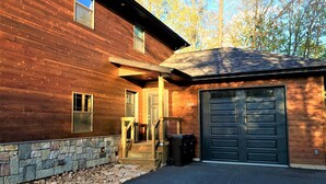 A wooden house with a stone foundation, a garage, and a stone wall. - Wooded Bliss @ Spring Brook Resort (Wisconsin Dells)