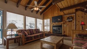 Una sala de estar acogedora con chimenea, muebles de madera y ventanas amplias.