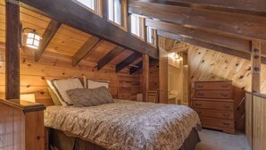 Un dormitorio acogedor de madera con cama, cómoda y mesitas de noche.