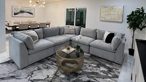 Un salon moderne avec un canapé d’angle, une table basse ronde et un tapis à motifs de marbre.