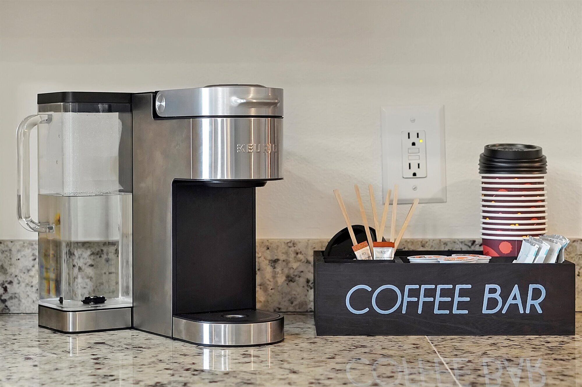 Una cafetería con una máquina de café, dispensador de agua y un portavasos.