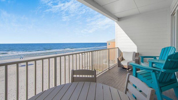 Una terraza de madera con vista a la playa y al océano.