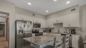 Una cocina moderna con armarios blancos, electrodomésticos de acero inoxidable y encimera de granito.