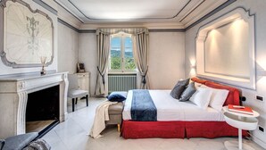 Un dormitorio con una cama grande, una chimenea, vistas al exterior y un espejo amplio.