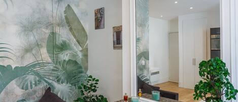 A modern living room with a large mirror, a marble fireplace, and a tropical mural.