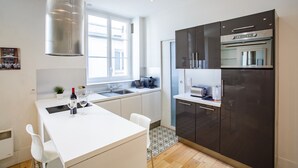A modern kitchen with a large island, stainless steel appliances, and a window providing natural light. - 2 Pièces Quartier Rue du Commerce, Proche Tour Eiffel (Paris)