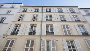 A multi-story building with white shutters on windows and balconies. - 2 Pièces Quartier Rue du Commerce, Proche Tour Eiffel (Paris)