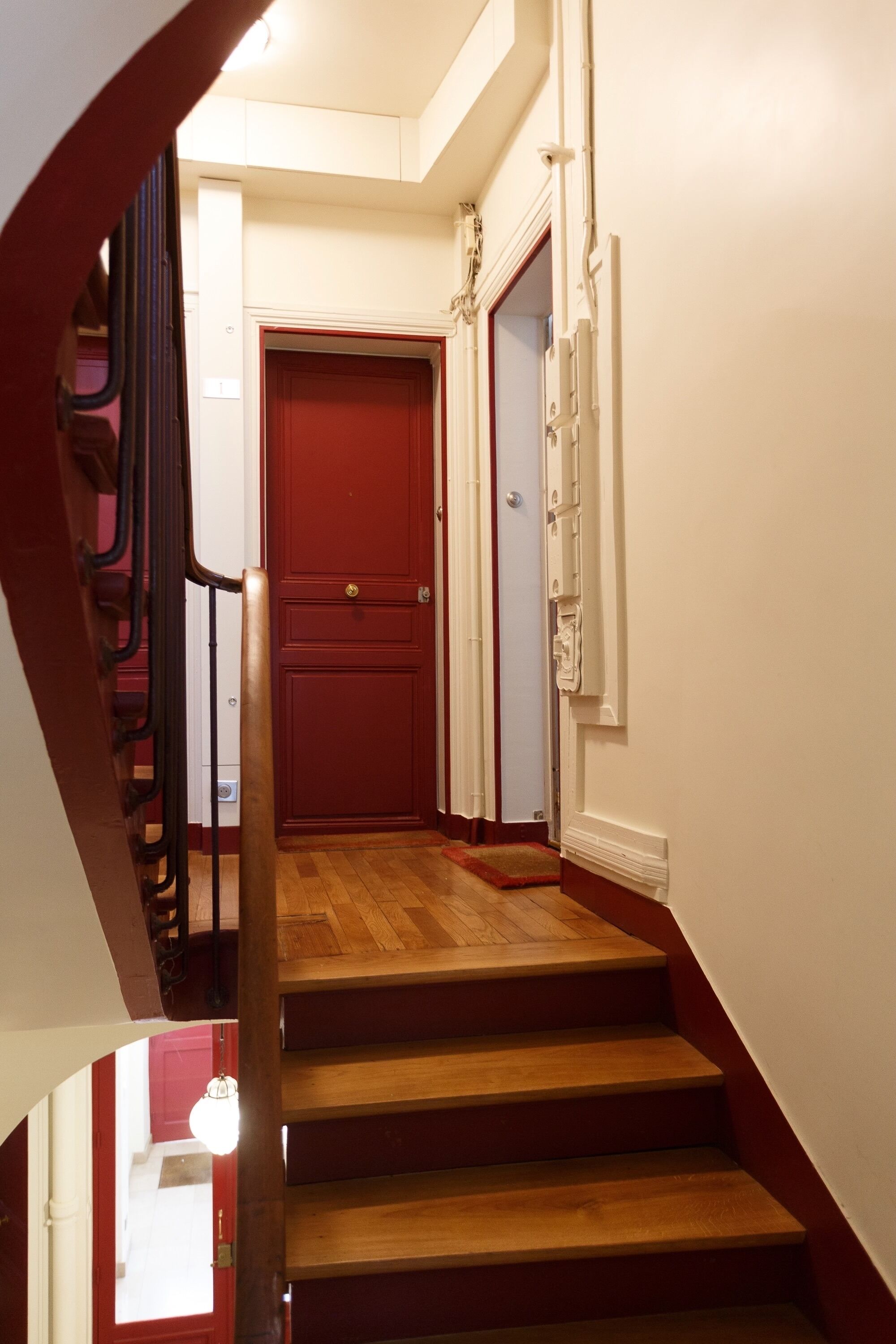 A staircase with wooden steps and a red door at the top.