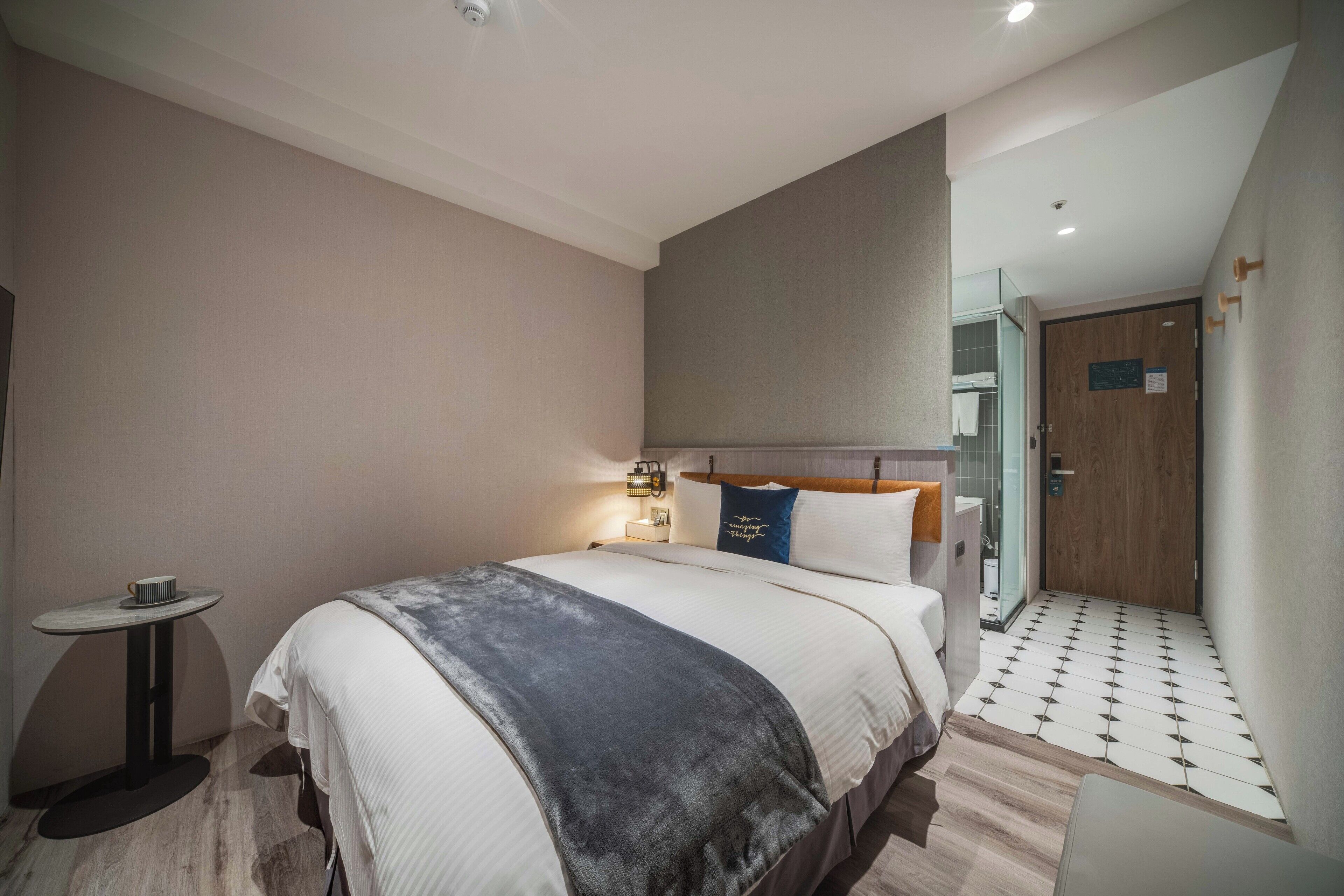 Ein modernes Hotelzimmer mit einem großen Bett, einem Nachttisch und einem kleinen runden Tisch.