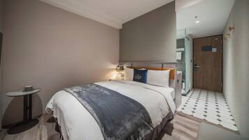 Ein modernes Hotelzimmer mit einem großen Bett, einem Nachttisch und einem kleinen runden Tisch.