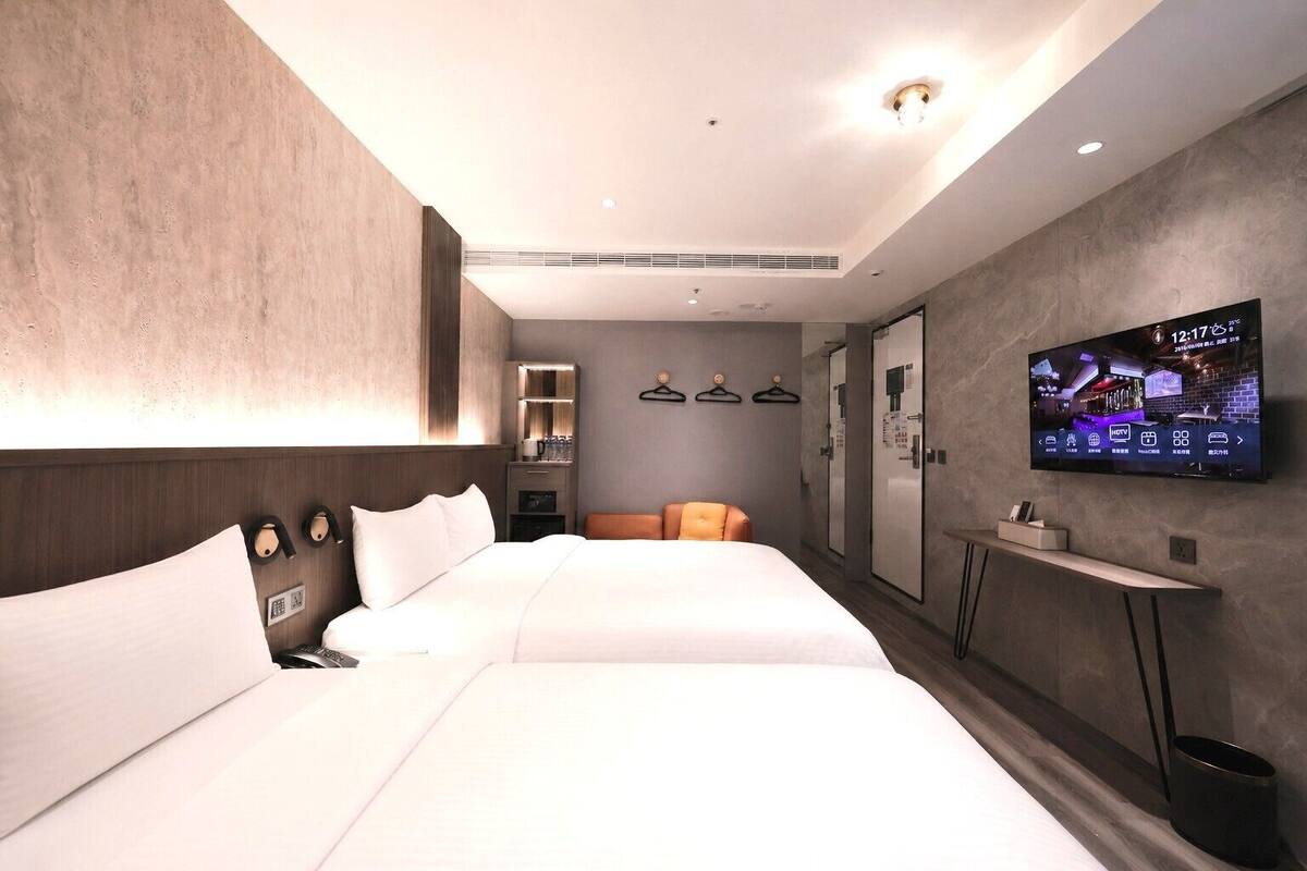 Een moderne hotelkamer met een groot bed, een televisie, een klein tafeltje en een spiegel.