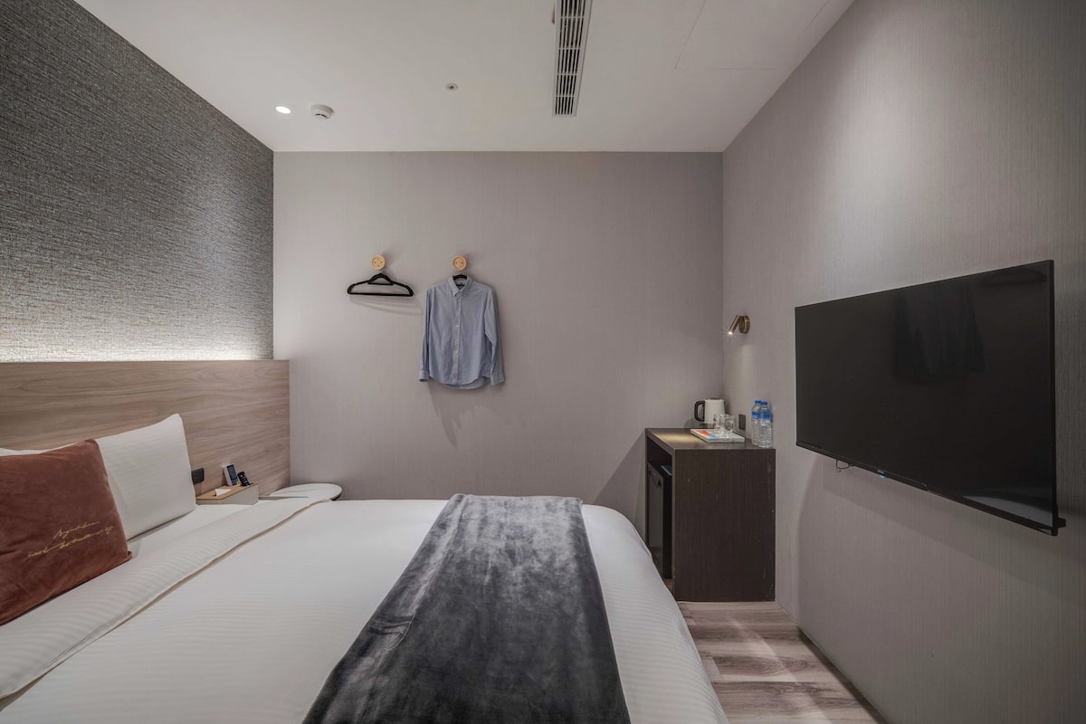 Een moderne hotelkamer met een groot bed, een flatscreen-tv, een bureau met koffiezetapparaat en een tv aan de muur.