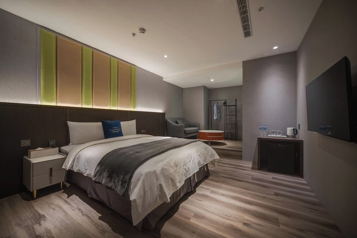 Een moderne hotelkamer met een groot bed, nachtkastje en een klein bureau met stoel.