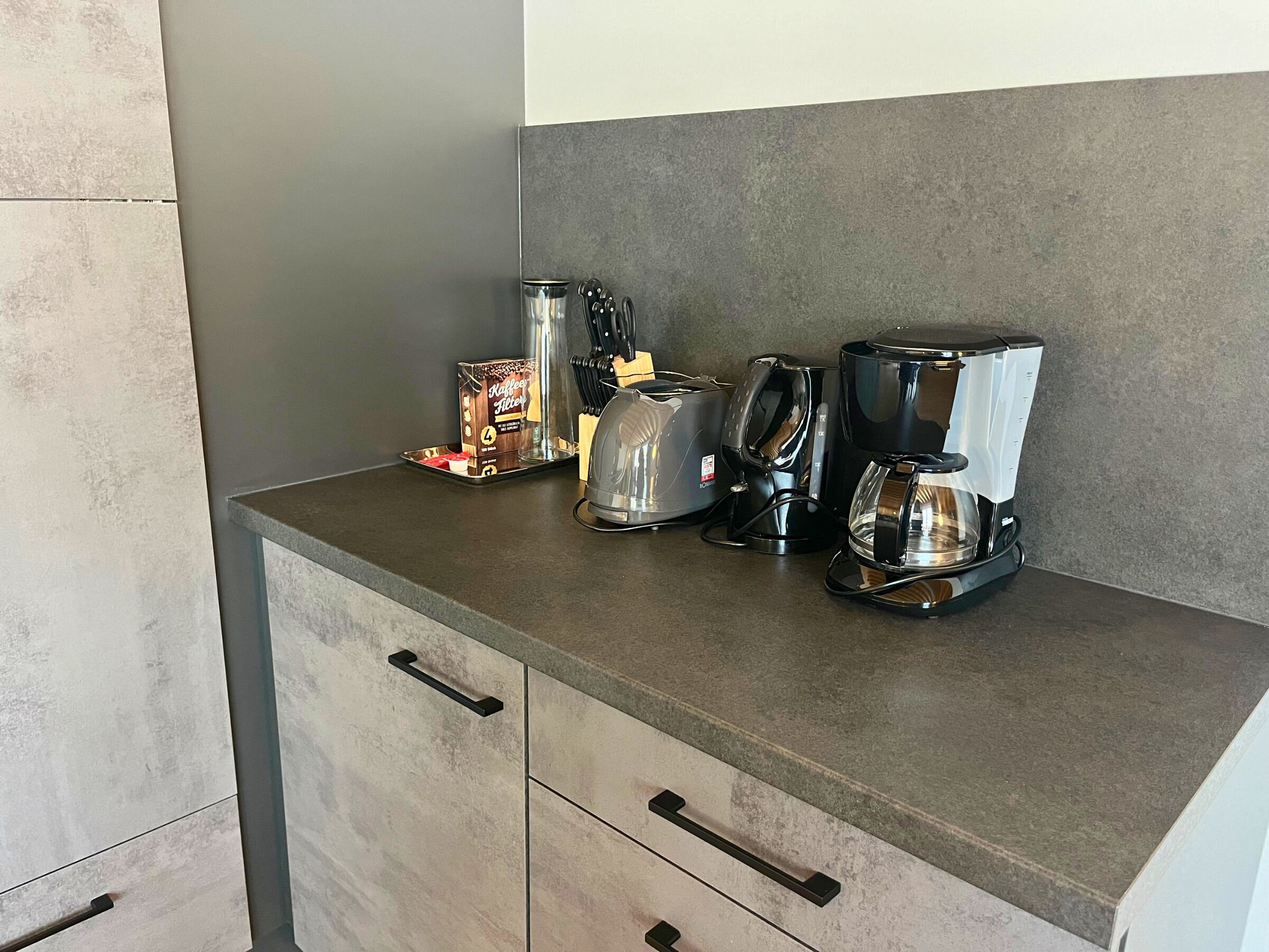A kitchen counter with a coffee maker, toaster, and a box of coffee creamer.